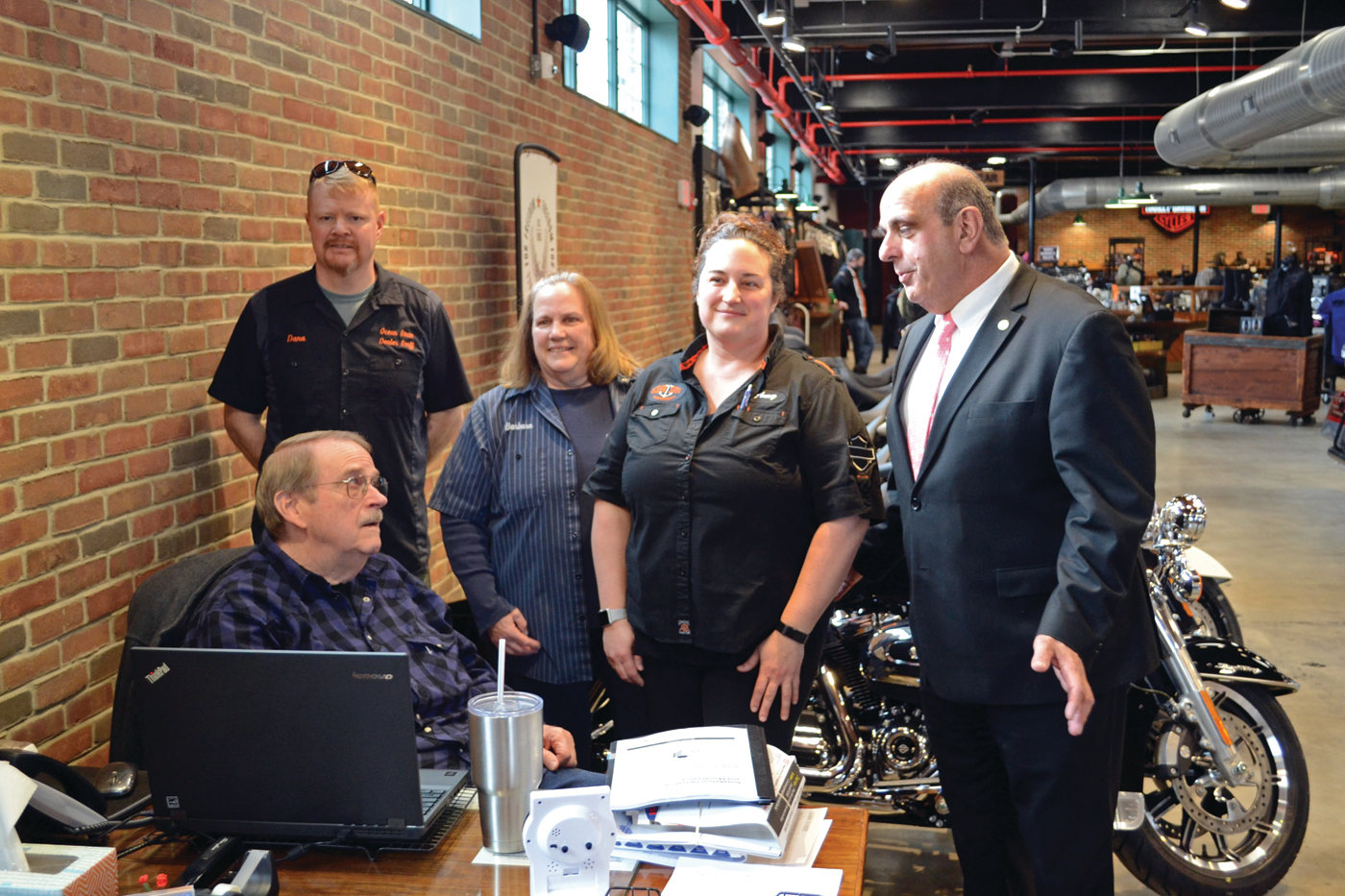 FAMILY BUSINESS: First generation owners Russ and Barbara Hamptom pose with their second generation, daughter Amy Bishop (owner) and her husband Dana, along with Mayor Solomon during his visit to Russ’ Ocean State Harley-Davidson on Tuesday.